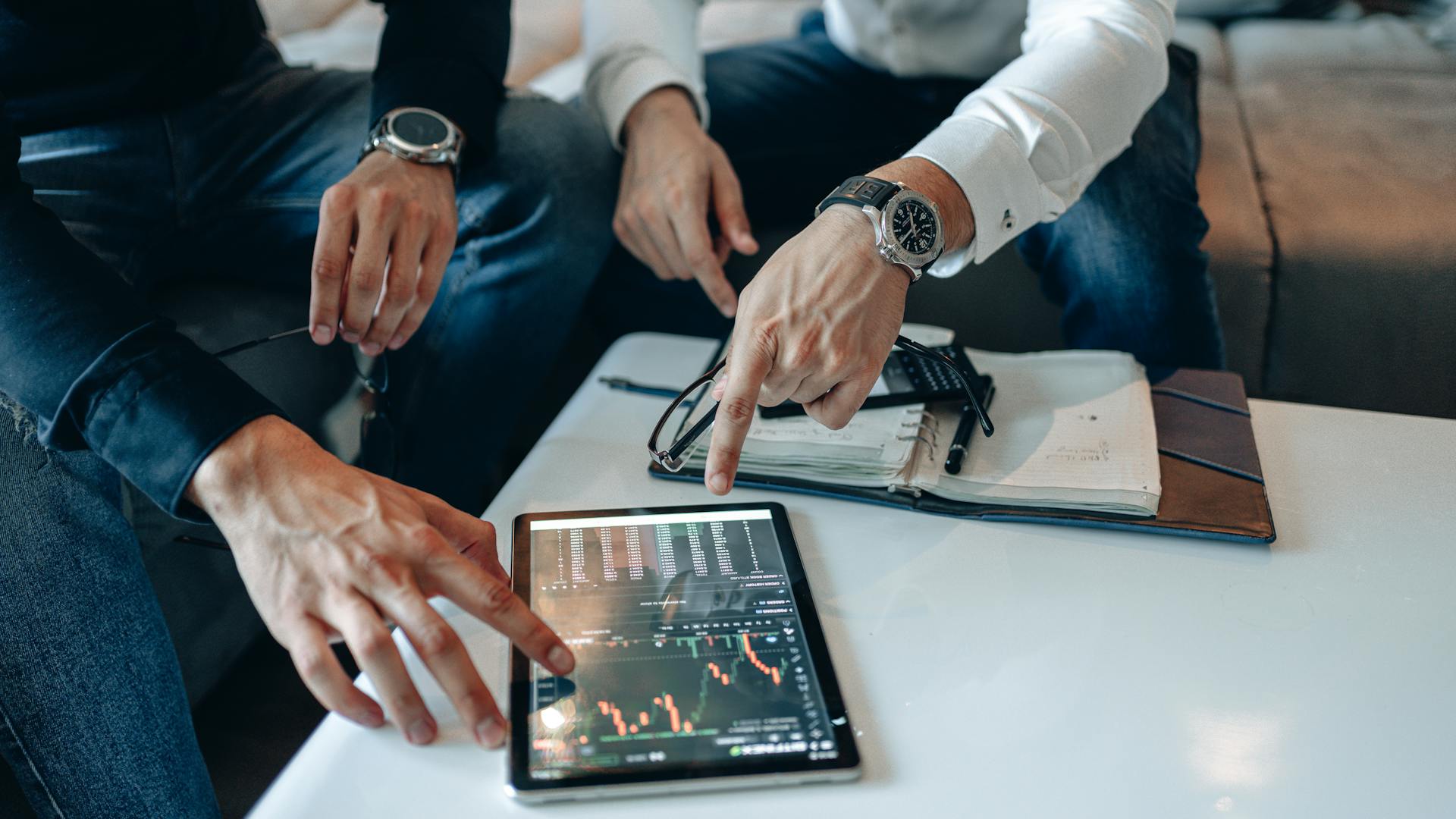 Investment professionals reviewing financial data and market charts on a tablet